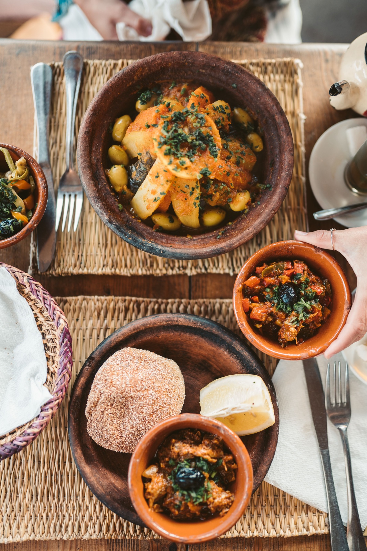 A Moroccan table filled with tagines, vegetables and bread